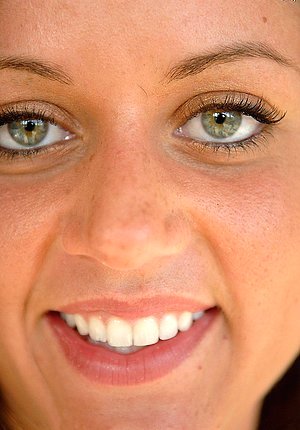 Brunette with a confident grin displaying her beautiful pussy on a bed